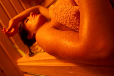 Frau liegt mit Handtuch in Sauna und schwitzt