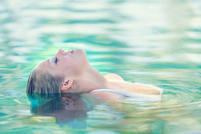 Frau liegt mit Kopf im Wasser und entspannt